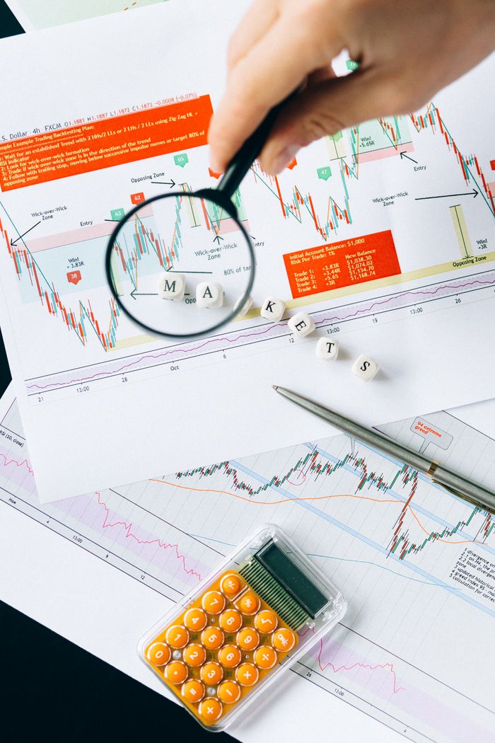 services-01 Magnifying glass focusing on market data and charts indicating financial analysis concept.
